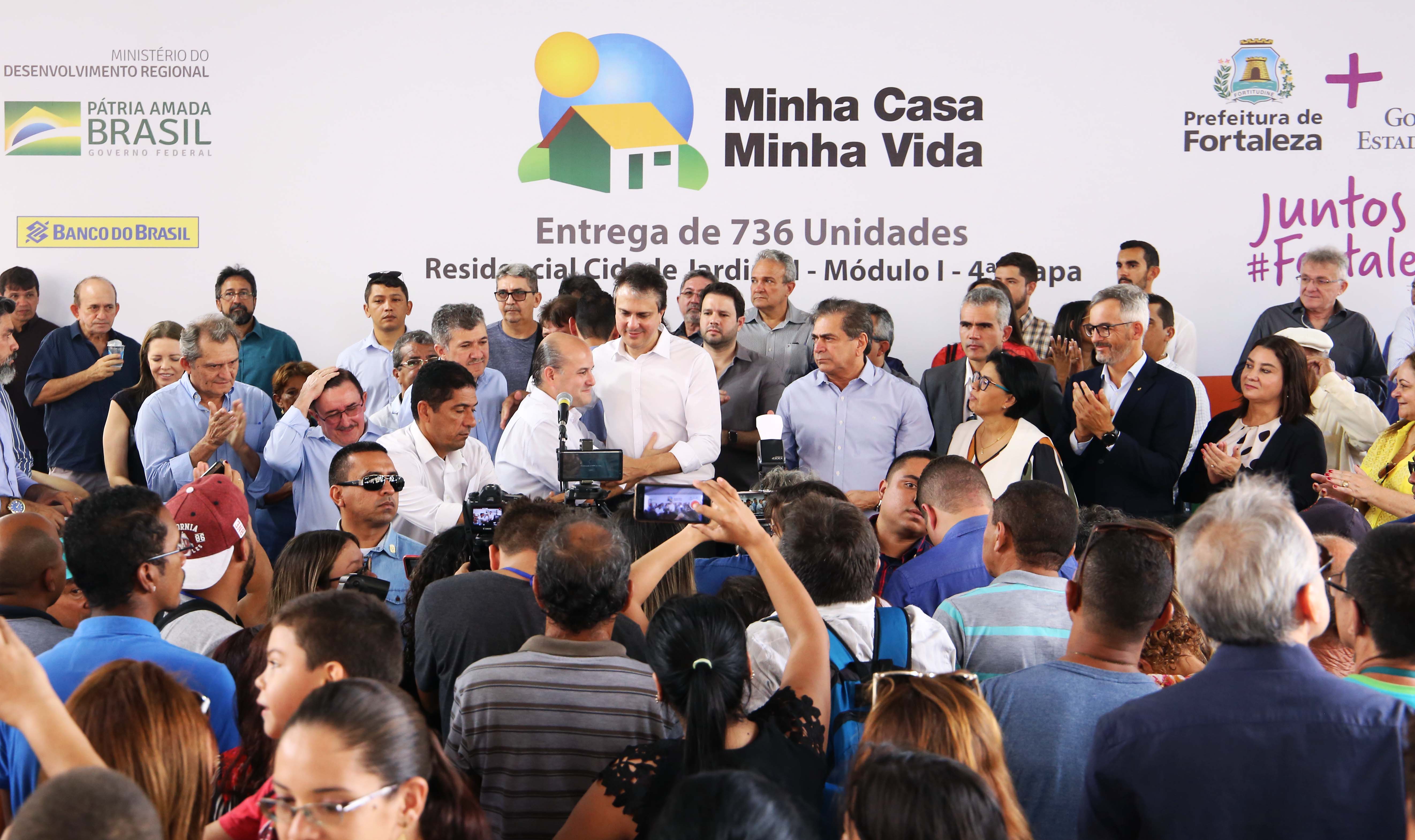 prefeito roberto cláudio e governador camilo santana se abraçam em um palco com dezenas de pessoas ao redor